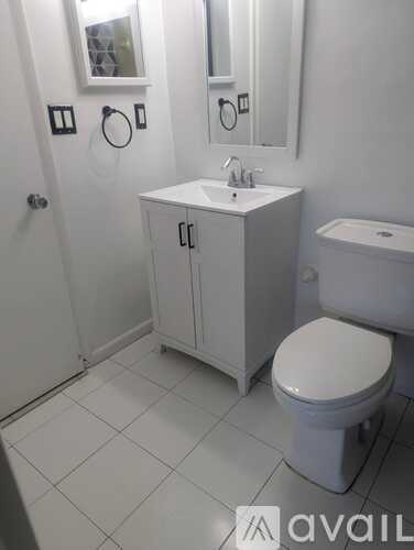 A white bathroom with a toilet, sink, and mirror.