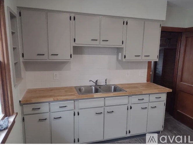A kitchen with white cabinets and a wooden countertop.