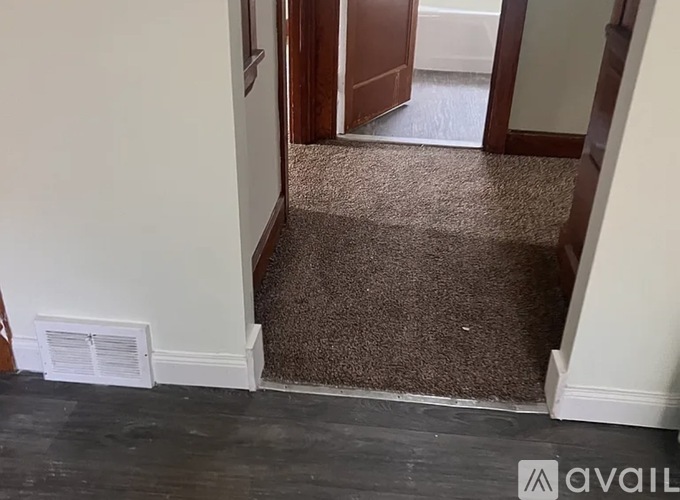 A hallway with a carpeted floor and a doorway leading to another room.