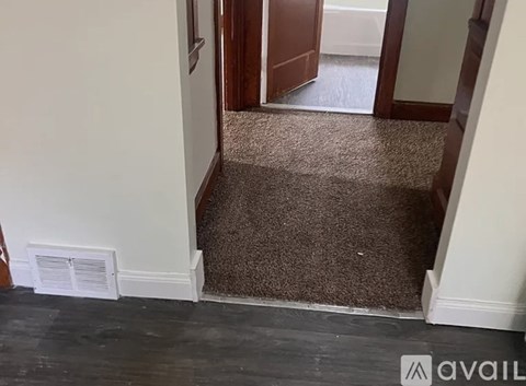 A hallway with a carpeted floor and a doorway leading to another room.