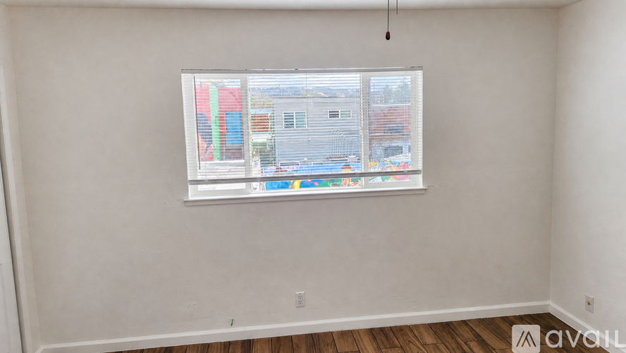 A room with a window that has a view of a street with buildings.