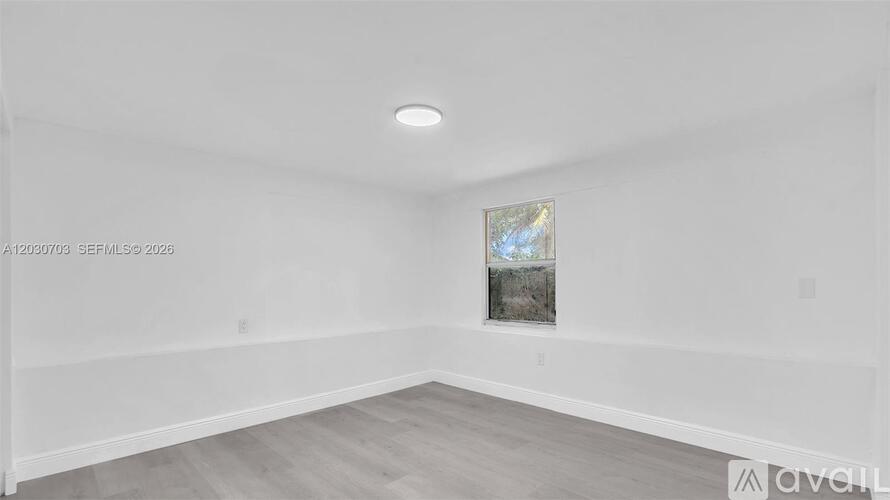 A spacious room with a window and a painting on the wall.