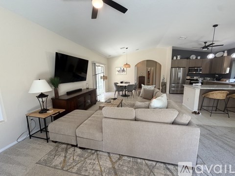 A living room with a beige couch and a flat screen TV mounted on the wall.