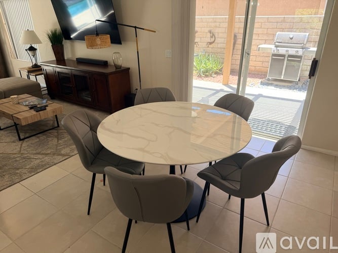 A modern dining room with a round table and grey chairs.