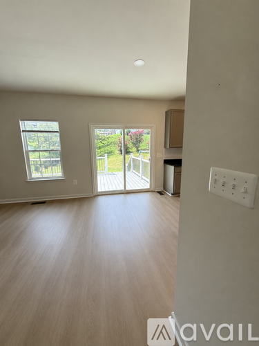 A room with a window and sliding glass doors leading to a backyard.