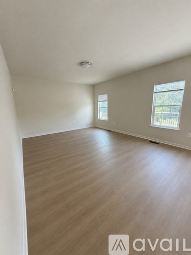 A room with wooden flooring and two windows.