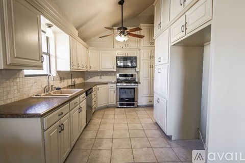 A kitchen with white cabinets and a fan on the ceiling.