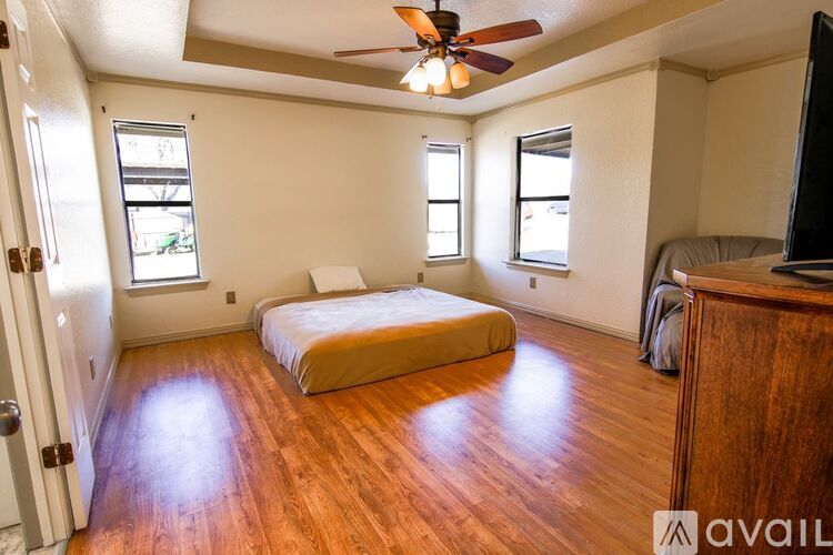 A bedroom with a bed, dresser, and a ceiling fan.