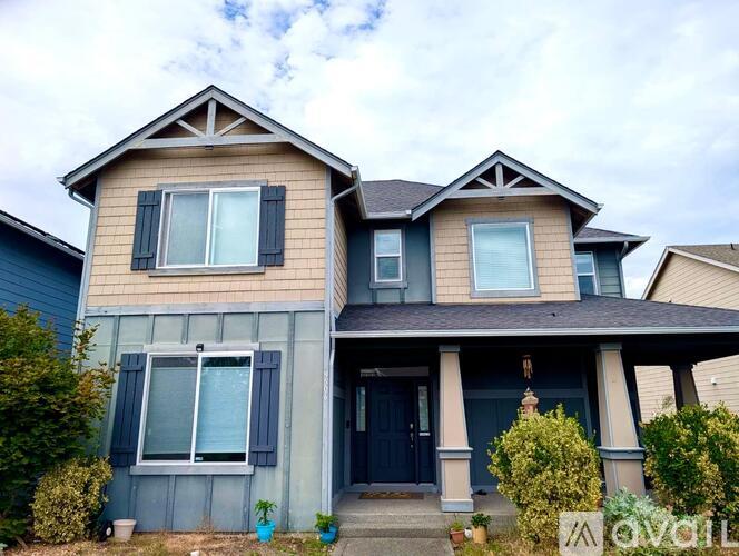 A two-story house with a dark blue front door and a small front porch.