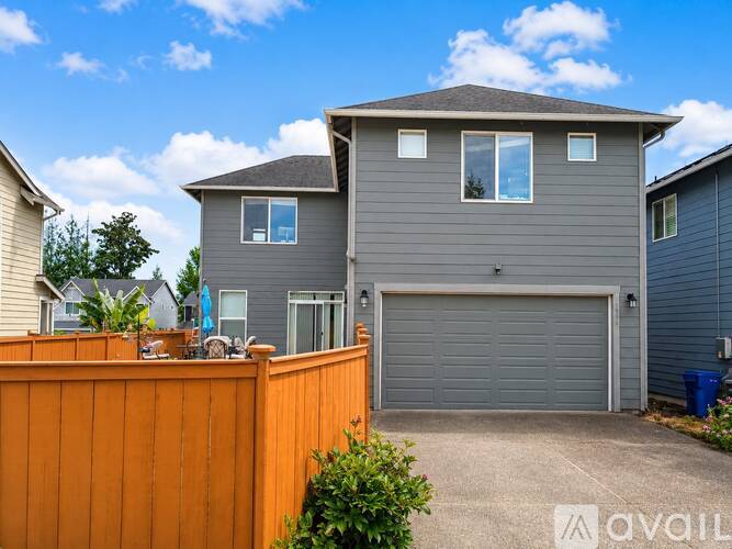 A grey house with a grey garage door and a brown fence.