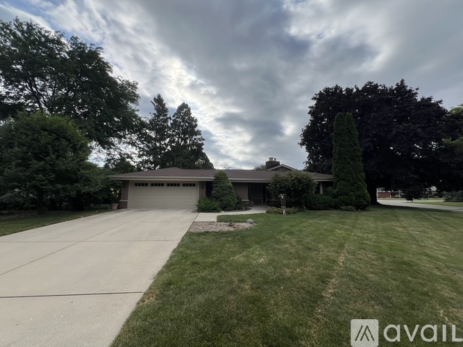 A house with a driveway and trees in the background.