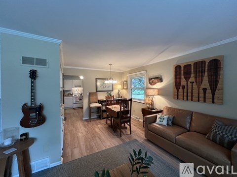 A living room with a brown couch and a guitar hanging on the wall.