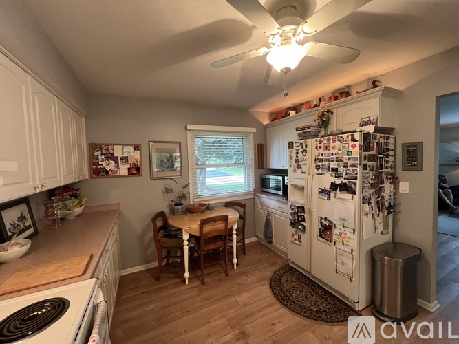 A kitchen with a refrigerator covered in magnets and a dining table with chairs.