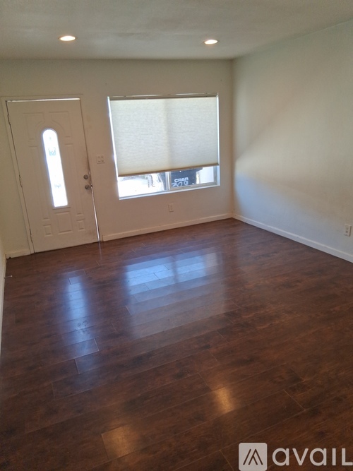 A room with wooden floors and a window with blinds.