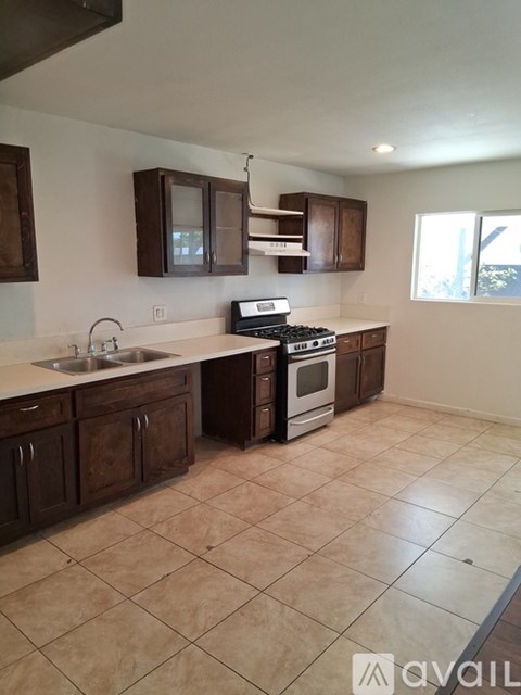 A kitchen with brown cabinets and a tiled floor.