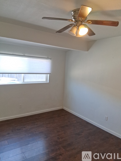 A room with a ceiling fan and a window with blinds.