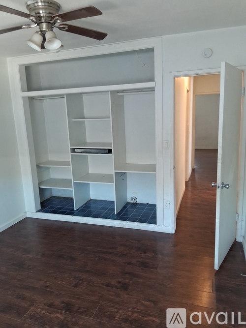 A room with a ceiling fan and a cabinet with shelves.