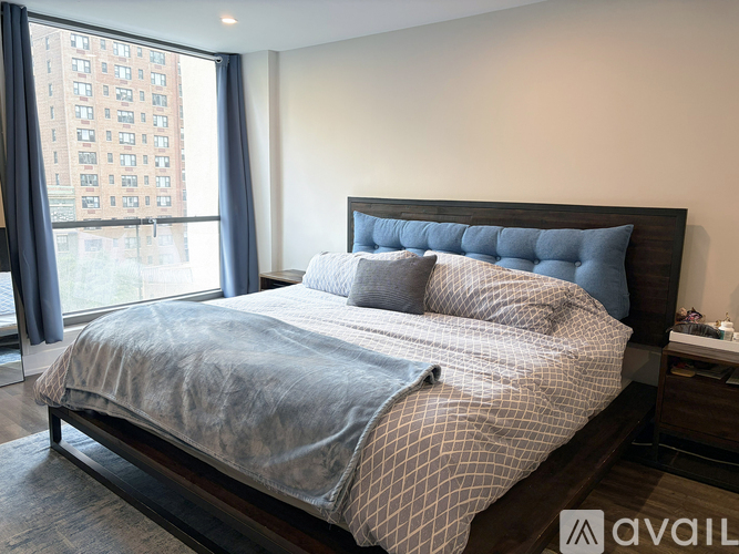 A bedroom with a large bed and a window overlooking a city.