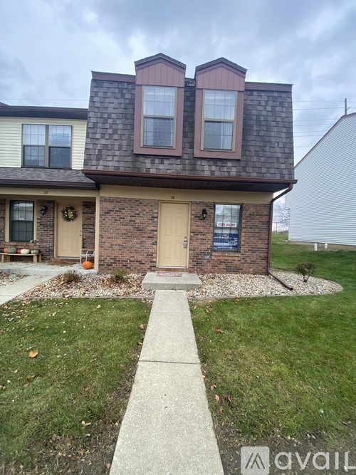 A two-story house with a brick facade and a brown door.