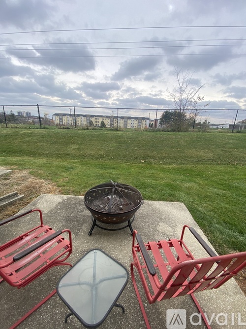 A red chair and a table with a grill on it are on a patio.