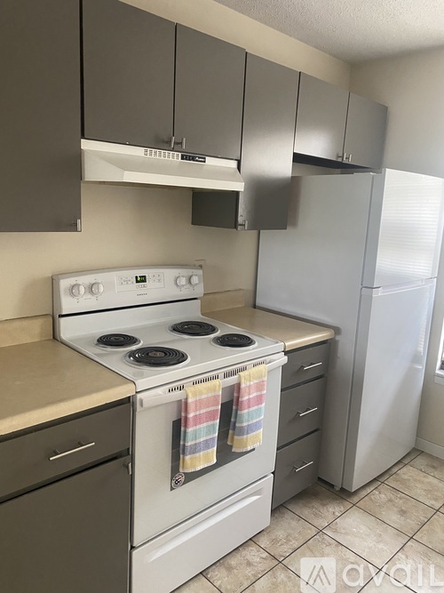 A kitchen with a white stove top oven and a white refrigerator.