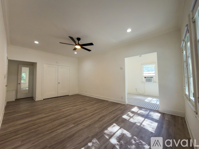 A spacious room with a ceiling fan and wooden flooring.