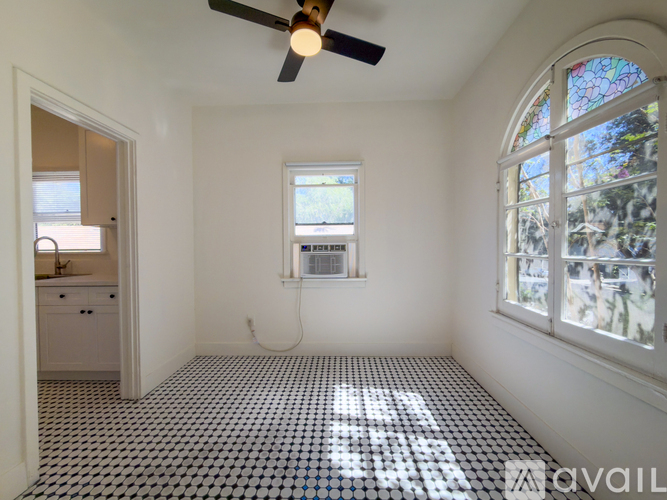 A room with a ceiling fan and a window with a view of trees.