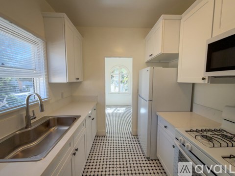 A kitchen with white cabinets and a black and white checkered floor.