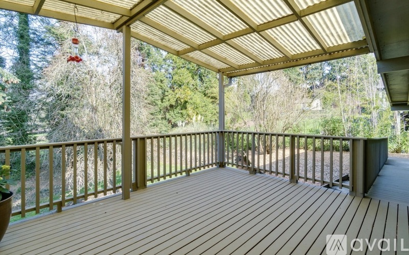 A wooden deck with a glass roof and a view of trees.
