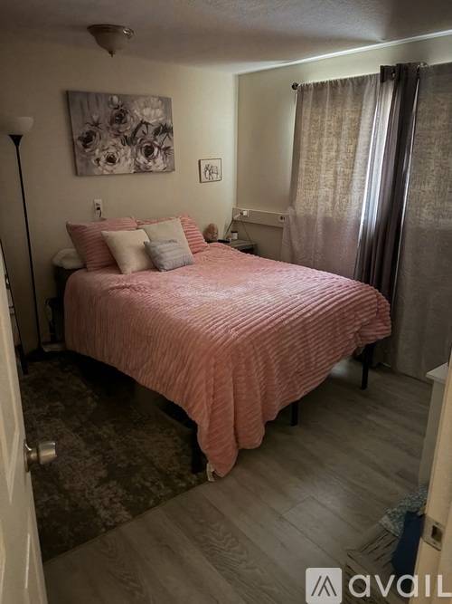 A bedroom with a bed, nightstand, lamp, and artwork on the wall.