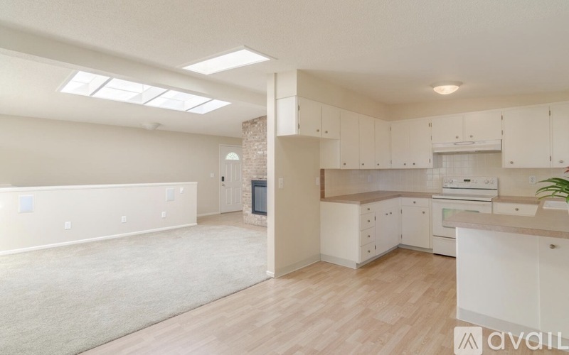 A spacious kitchen and living room with white cabinets and a skylight.