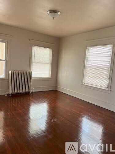 A room with wooden floors and a window with blinds.