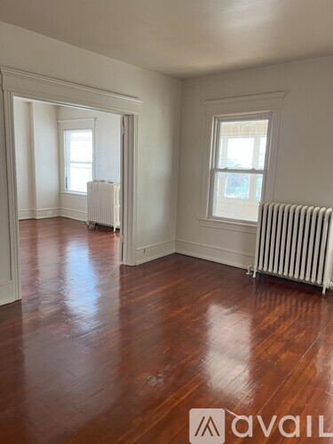 A room with wooden floors and two windows.