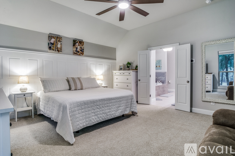 A bedroom with a large bed, a ceiling fan, and a mirror on the wall.
