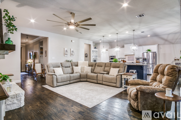 A living room with a brown sofa and a ceiling fan.