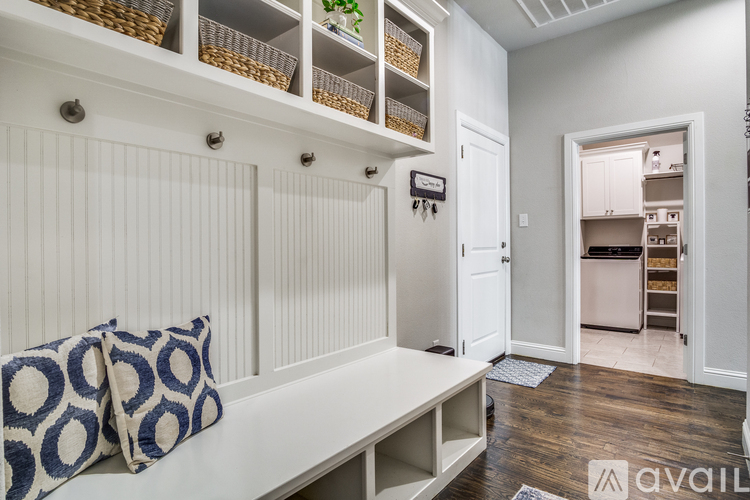 A kitchen with white cabinets and a bench with a blue and white pillow.