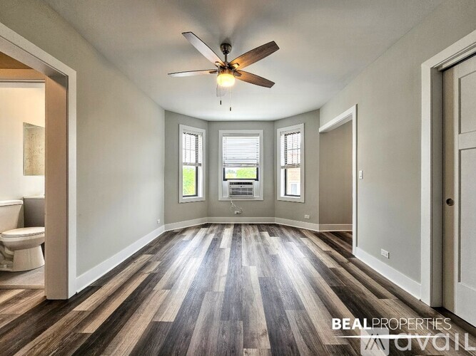 A spacious room with a ceiling fan and wooden flooring.