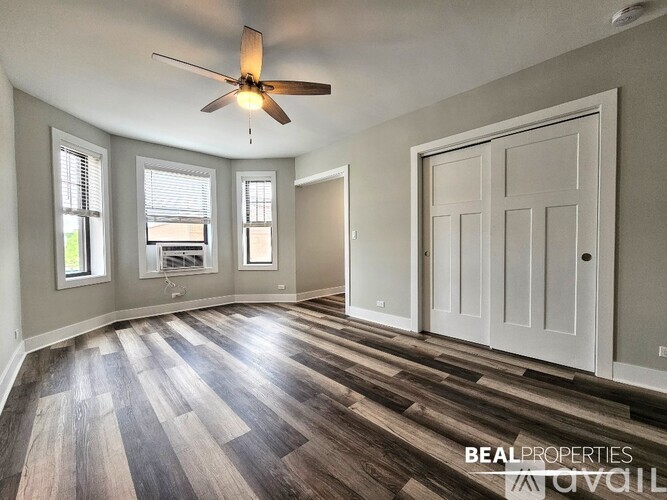 A room with a ceiling fan and wood flooring.