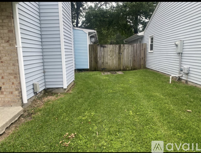 A backyard with a wooden fence and a grassy area.