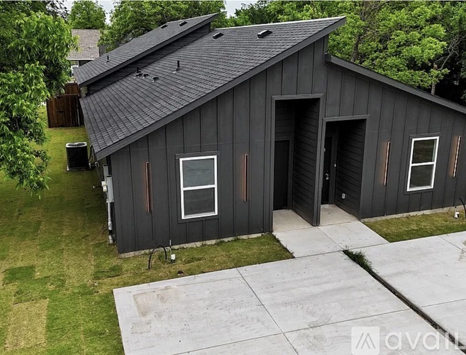 A black wooden house with a grey roof and a white door.