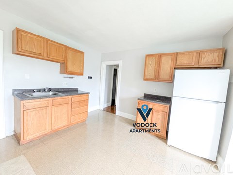 A kitchen with wooden cabinets and a white fridge is shown.