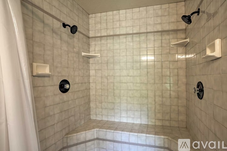 A bathroom with a shower and a white tile wall.