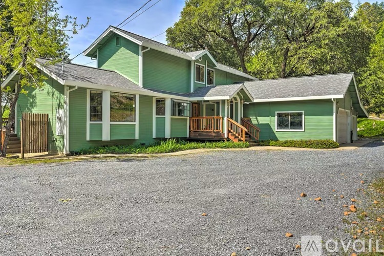 A house with a green exterior and a gravel driveway.