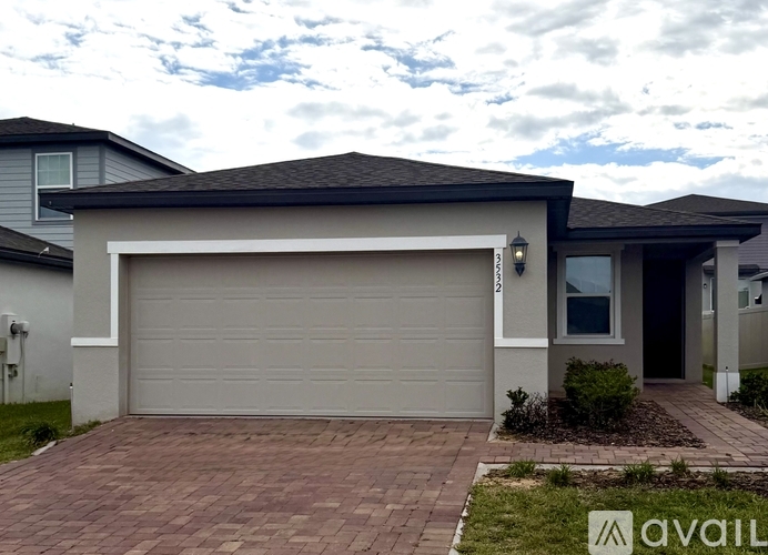 A house with a garage door and a brick driveway.
