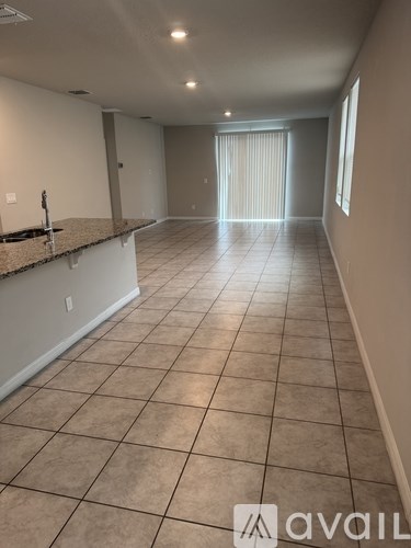 A spacious room with tiled flooring and a countertop.