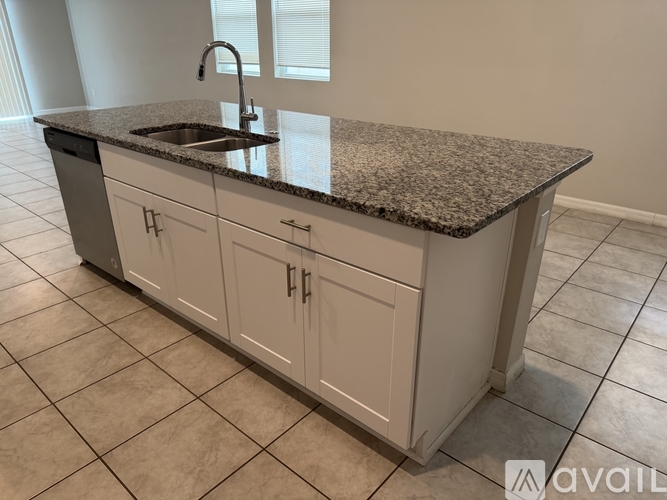 A granite countertop with a sink and white cabinets.