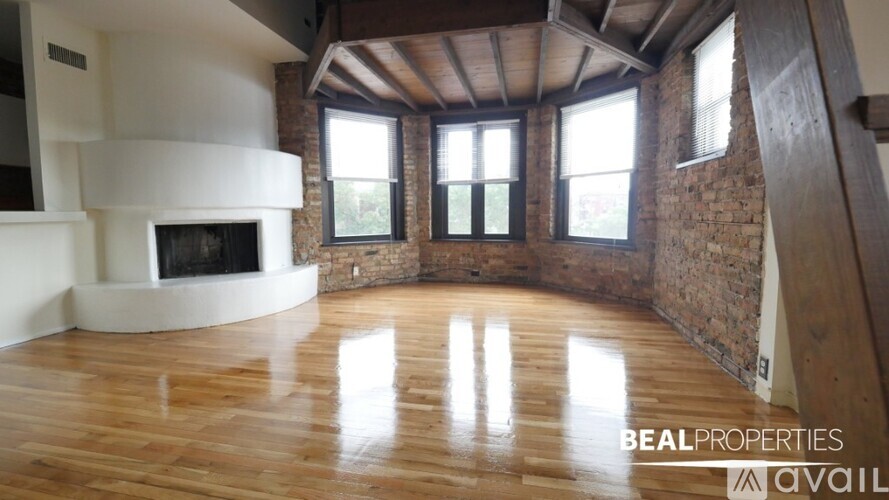 A spacious room with wooden floors and a brick wall.
