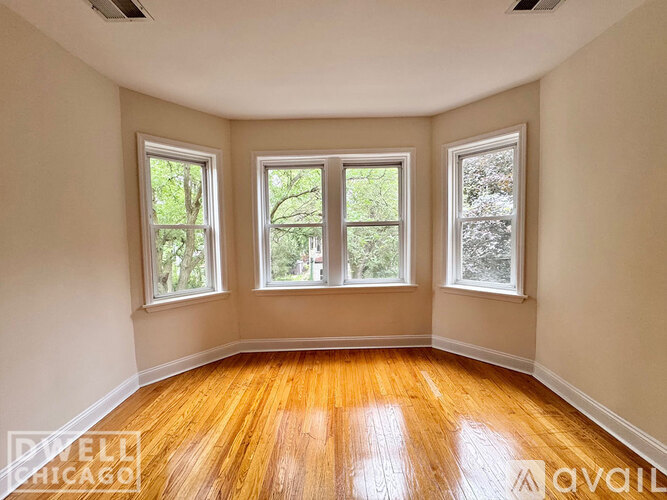 A room with wooden floors and three windows.