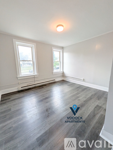 A room with wooden flooring and two windows is available for rent.