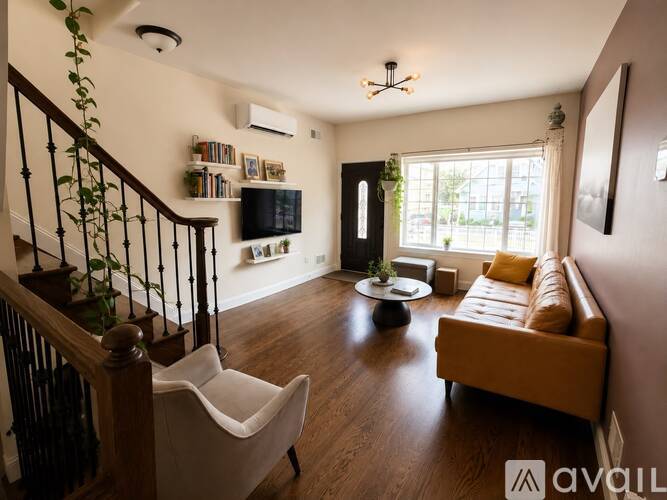 A living room with a brown leather couch and a white chair.